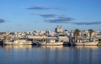 View of Naoussa, Fishing boats in the harbour at sunset, reflected in the sea, White Cycladic