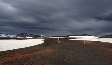 Hikers in snow-covered volcanic landscape with volcanic sand and petrified lava, crater of Askja