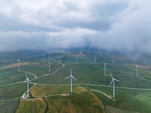 Windmills on a wind farm near Zahara de los Atunes, at a cloudy dawn, aerial view, drone shot,