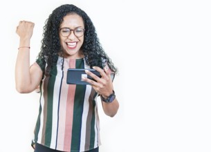 Excited young afro girl holding phone celebrating something. Happy afro woman holding smartphone