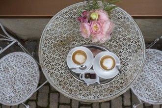 Two cappuccinos with flowers on a bistro table, Bavaria, Germany, Europe