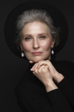 Portrait of a beautiful elderly woman in a white shirt with classic makeup and gray hair