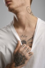 Cropped image of young tattooed man pulling his t-shirt