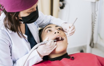 Female dentist cleaning and examining a female patient mouth. Dental specialist cleaning the teeth