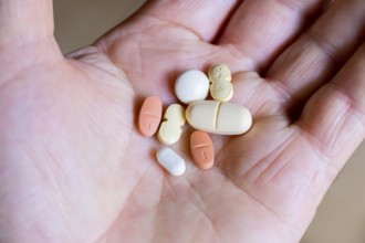 Hand holding various tablets, medicines, drugs