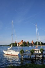 Yacht boats and Trakai Island Castle in lake Galve in day, Lithuania. Trakai Castle is one of major