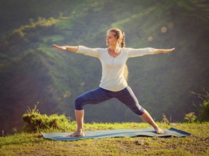 Yoga outdoors, sporty fit woman doing yoga asana Virabhadrasana 2, Warrior pose posture outdoors in