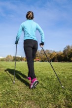 Nordic walking adventure and exercising concept, woman hiking withnordic walking poles in park