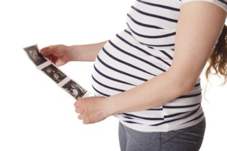 Pregnant woman standing and holding her ultrasound baby scan picture isolated on white