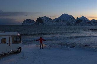 Motorhome in winter on pitch with view of fjord and snow-capped mountains, Storsandnes Beach,