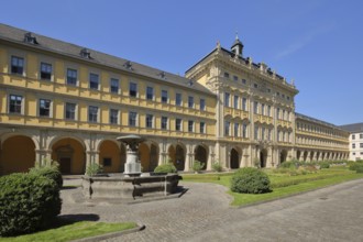 Inner courtyard and fountain with baroque princely building with arcade and gardens of the