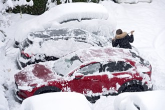 Woman removes fresh snow from car with broom, car, snowed in, heavy snowfall, snow masses, snow