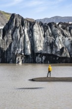 Tourist at the lakeside of a glacier lagoon, glacier tongue with crevasses and lake,