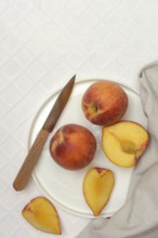 Cut peaches with knife on plate (Prunus persica)