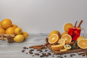 Wooden board with oranges and lemons, punch in a glass cup, spices, light background, copy room