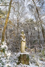 Stone sculpture of a grieving woman in the snow, Südwest-Kirchhof, historic cemetery in Stahnsdorf,