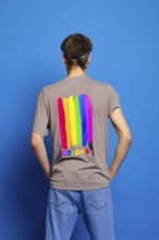 Back view of young man in t-shirt with lgbtq flag on blue background