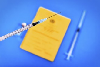 Vaccine concept with syringe in front of blurry vial and yellow international certificate of