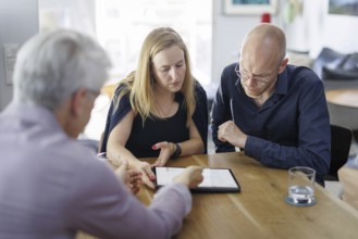 Symbolic photo on the subject of counselling. A young woman and a young man sit together at a table