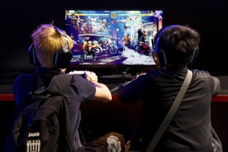 Two young visitors in front of a screen with a computer game, Gamescom trade fair, the world's