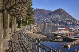 Lakeside promenade, railing with shade, trees, lake, mountain, mist, blue sky, Lake Lugano, Lugano,