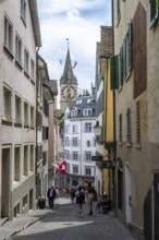 Narrow alley in the old town of Zurich, behind the tower of the historic parish church of St Peter,