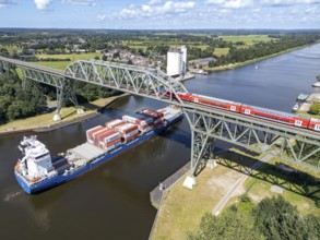 Aerial view of the Hochdonn bridge over the Kiel Canal with regional railway and container ship in