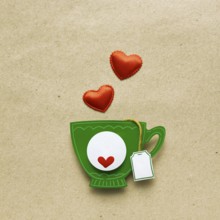 Creative valentines concept photo of a cup of tea with paper hearts on a brown background