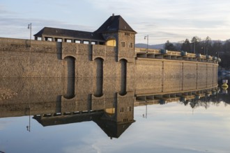 Edertalsperre in autumn, evening sun illuminates the dam yellow, which is reflected in the water,