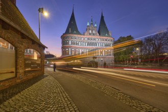 City gate Lübeck Holstentor, historic brick building, footpath and cycle path, light traces of a