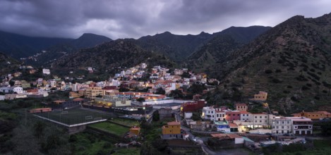 View of Vallehermoso and the surrounding mountain landscape at dusk under a cloudy sky.