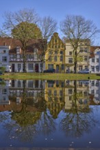 Historic houses, symmetrical reflections on the water surface, river Trave, cloudless blue sky, old