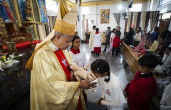 Archbishop John Moolachira holds an idol of baby Jesus Christ as devotees kiss the idol during a