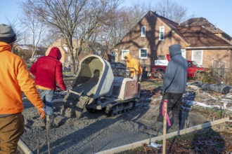 Detroit, Michigan - Workers pour and finish concrete for walking paths in Three Mile Park in