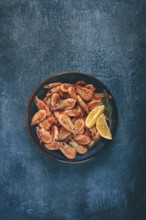 Fried shrimp, with shell and head, unpeeled, size 70-90, on a blue background, homemade, no people