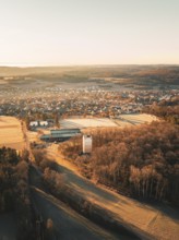 Aerial view of a village with surrounding fields and forests at sunset in autumnal atmosphere,