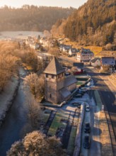 Picturesque village by the river with historic church and autumn landscape in the morning sun,