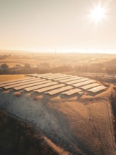 Solar panel fields on a hill at sunrise with a wide landscape in the background, Magstadt, Germany,