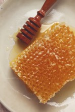 Honeycomb, with a wooden spoon-spindle, on a plate, no people