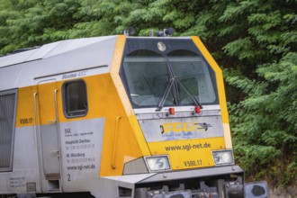 Yellow and grey locomotive on rails in front of a green landscape, track construction, Hermann