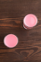 Sweet strawberry liqueur in glass on a brown wooden background. top view, close up, flat lay