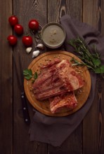 Smoked pork ribs, on a wooden table, top view, sauce, tomatoes and spices, close-up, vertical, no