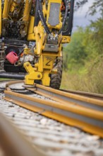 Yellow construction machine working on a railway track on ballast, track construction, Hermann