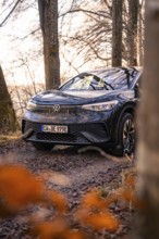 Car parked between trees, autumn leaves in the foreground, car sharing, electric car, Volkswagen ID