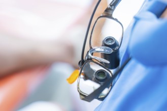 Close-up of medical magnifying glasses worn over a blue gown, dental practice, Germany, Europe