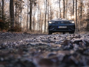 A car from the front on a frosty forest path at sunrise, car sharing, electric car, Volkswagen ID