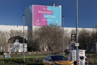 E-charging station and large poster for climate steel at the ThyssenKrupp Steel Europe plant,