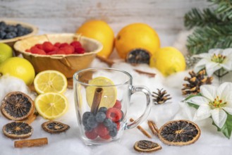 Glass with fresh berries, oranges and lemons in the background, Christmas decoration