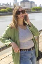 Vertical image of a young woman in a green jacket and sunglasses, looking at the camera while