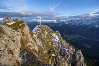 Mountaineer at the summit of the Kramerspitz with summit cross, at sunset, in autumn, Ammergau